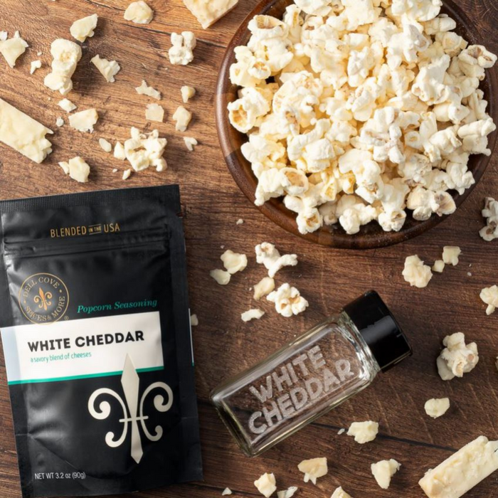 White cheddar popcorn seasoning pouch with bowl of popcorn and empty spice jar - dell cove spices
