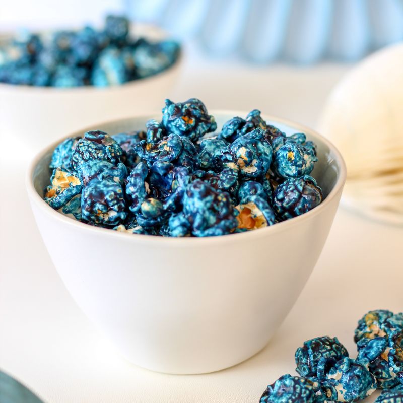 Naturally blue popcorn served in baby shower treat cups on a white table with pastel decorations.