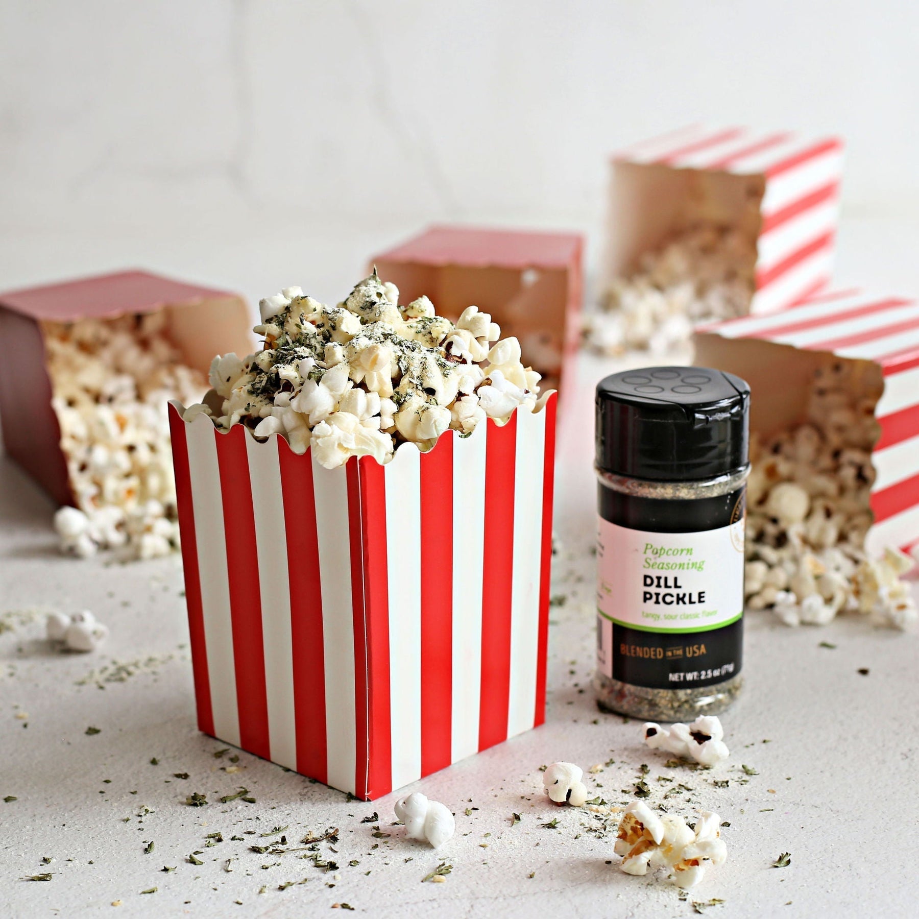 Popcorn box of Cool Ranch Popcorn, made with homemade ranch seasoning on top of Dell Cove Spices Rainbow popped kernels and Dell Cove Dill Pickle seasoning.