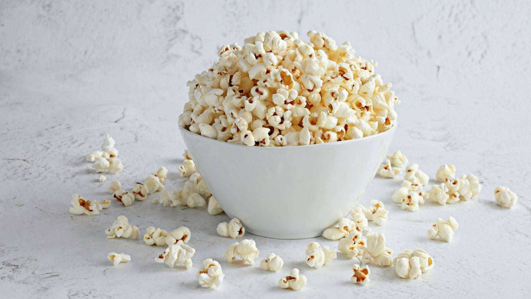 White bowl filled with popcorn on a light gray background - Dell Cove Spices