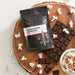 Dell Cove Chocolate Caramel Popcorn Seasoning with chocolate, popcorn and a bowl of chocolate-seasoned popcorn.