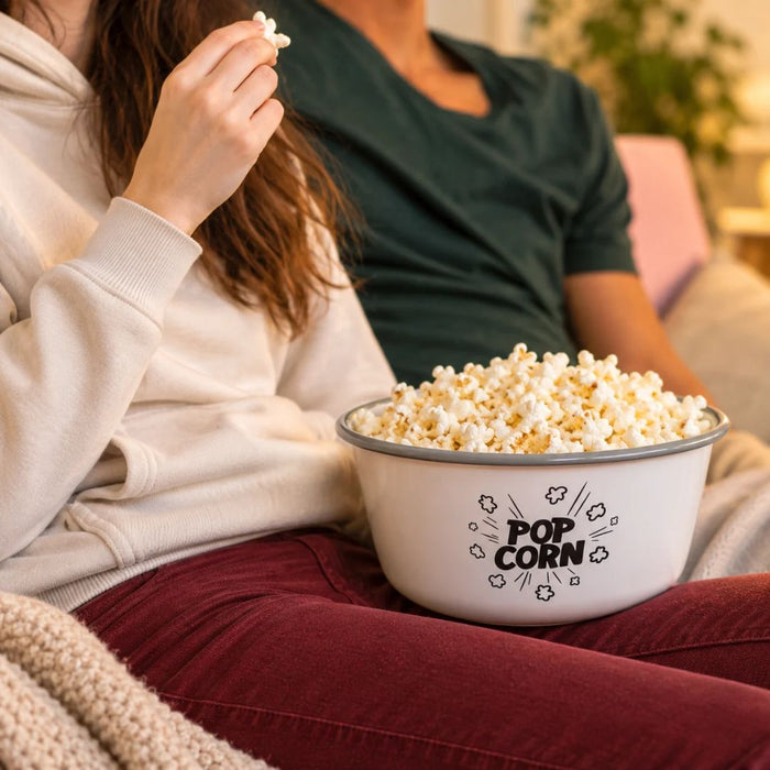 Two people enjoying freshly popped popcorn together on the couch during a cozy movie night at home.