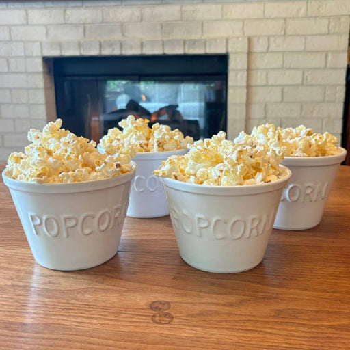 Set of four white Crate & Barrel ceramic popcorn bowls with raised POPCORN lettering
