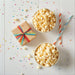 Dell Cove birthday popcorn gift collection, showing two bowls of popcorn with a small gift box and straws on a light surface with colorful confetti.