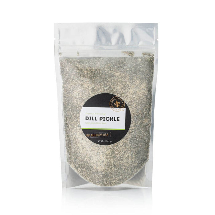 Close-up of Dell Cove Dill Pickle Popcorn Seasoning showing coarse popcorn salt texture with visible dill herbs and spices.