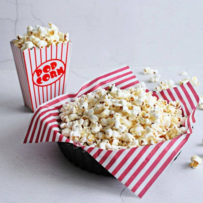 Popcorn in a red and white striped container on a light gray background