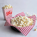 Popcorn in a red and white striped container on a light gray background