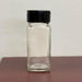 Empty Dell Cove glass spice jar with black flip-top sifter lid