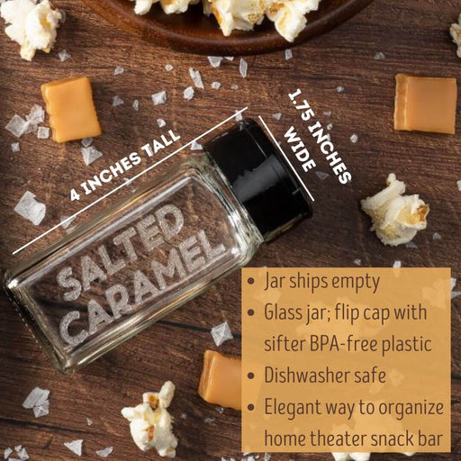 Glass spice jar etched Salted Caramel for salted caramel popcorn seasonings on a wooden surface with popcorn and caramel pieces.