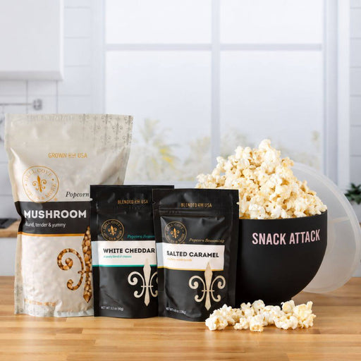 Dell Cove Family Popcorn Gift Set with Mushroom popcorn kernels, White Cheddar and Salted Caramel seasonings, and a black Snack Attack microwave popcorn popper filled with popcorn.