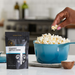Kettle Corn popcorn seasoning pouch with popcorn in a blue pan and a hand picking some up - dell cove spices