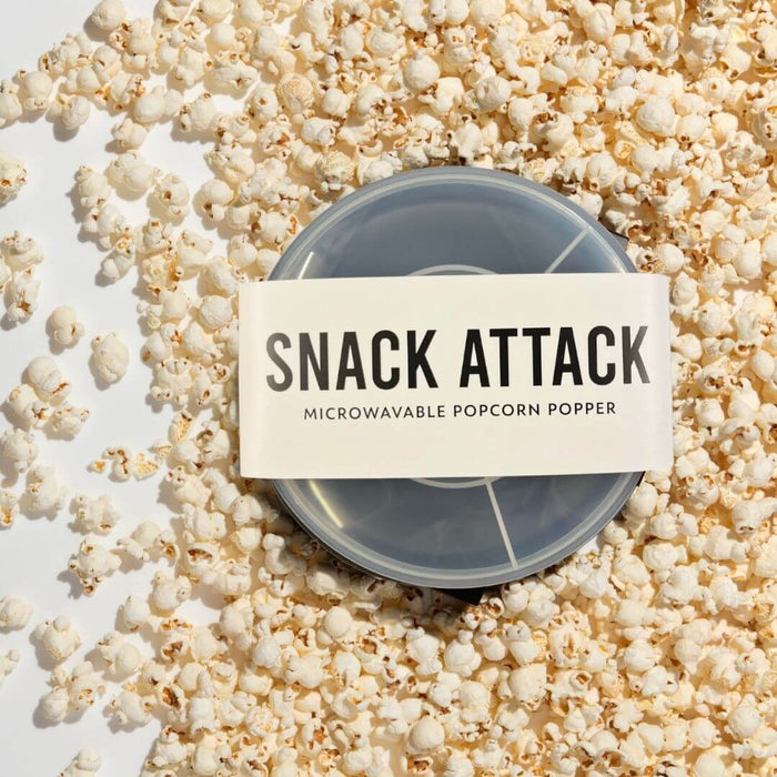 Snack Attack silicone microwave popcorn popper in packaging surrounded by freshly popped popcorn