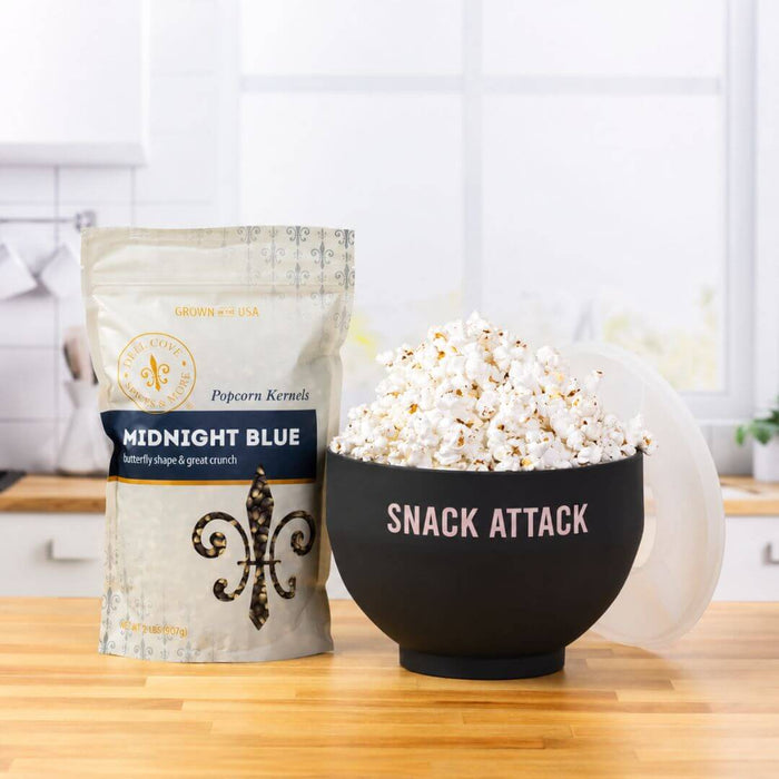 Dell Cove Midnight Blue popcorn kernels beside a black Snack Attack microwave popcorn popper filled with freshly popped popcorn.