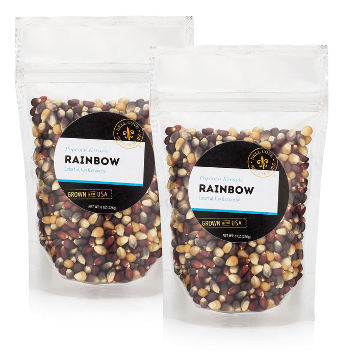 Two packages of Rainbow popcorn kernels with a Dell Cove Spices & More Co brand logo on a white background