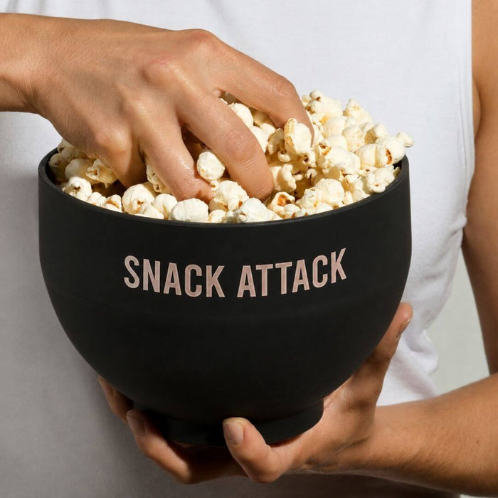 Reusable black silicone microwave popcorn bowl filled with fresh popcorn and held for snacking