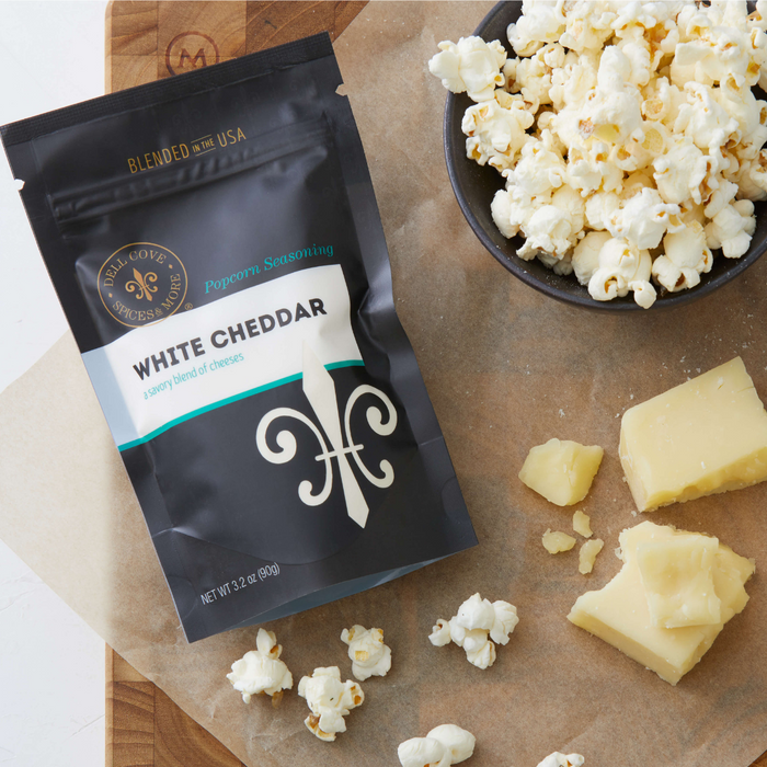 White Cheddar popcorn seasoning with cheese and popped popcorn in a bowl - dell cove spices