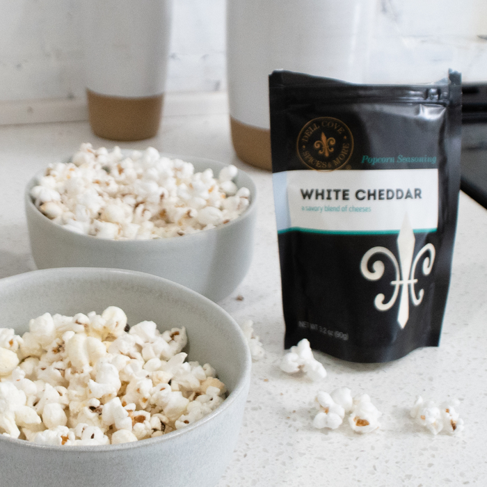 White cheddar popcorn seasoning with two bowls of popped popcorn - dell cove spices