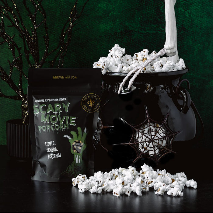 Skeleton hand holding Dell Cove® Zombie Movie Popcorn kernels – spooky photo prop for Halloween movie gift set.