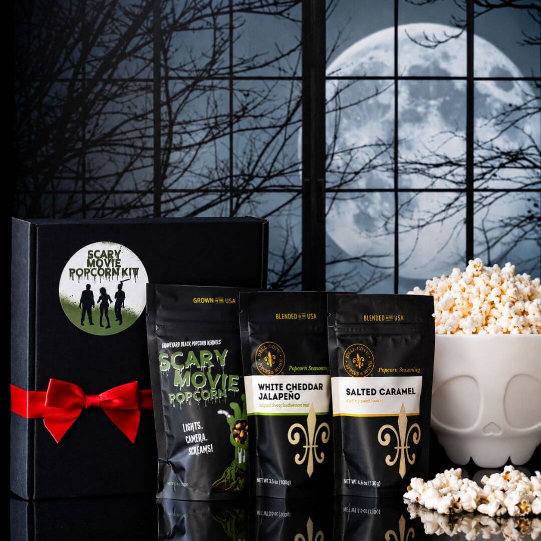 Dell Cove Zombie Movie Popcorn Kit with Graveyard Black popcorn kernels, two seasoning pouches, black gift box with red ribbon, and optional white skeleton-shaped popcorn popper filled with popcorn.