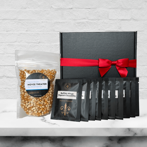 Black gift box with 10 mini seasoning packs in front and next to an 8 ounce bag of movie theater popcorn kernels. Dell Cove Spices