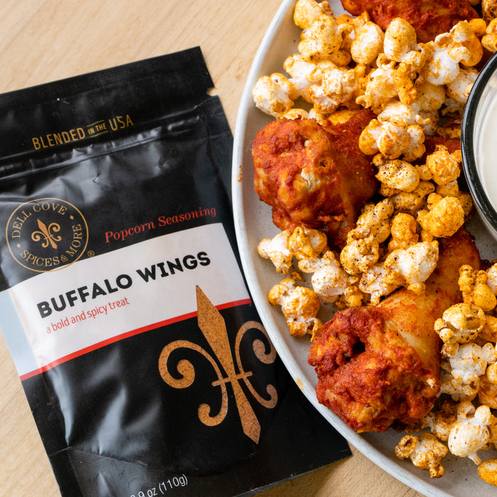 Buffalo Wings seasoning pouch laying next to seasoned popcorn and buffalo chicken wings. Dell Cove Spices